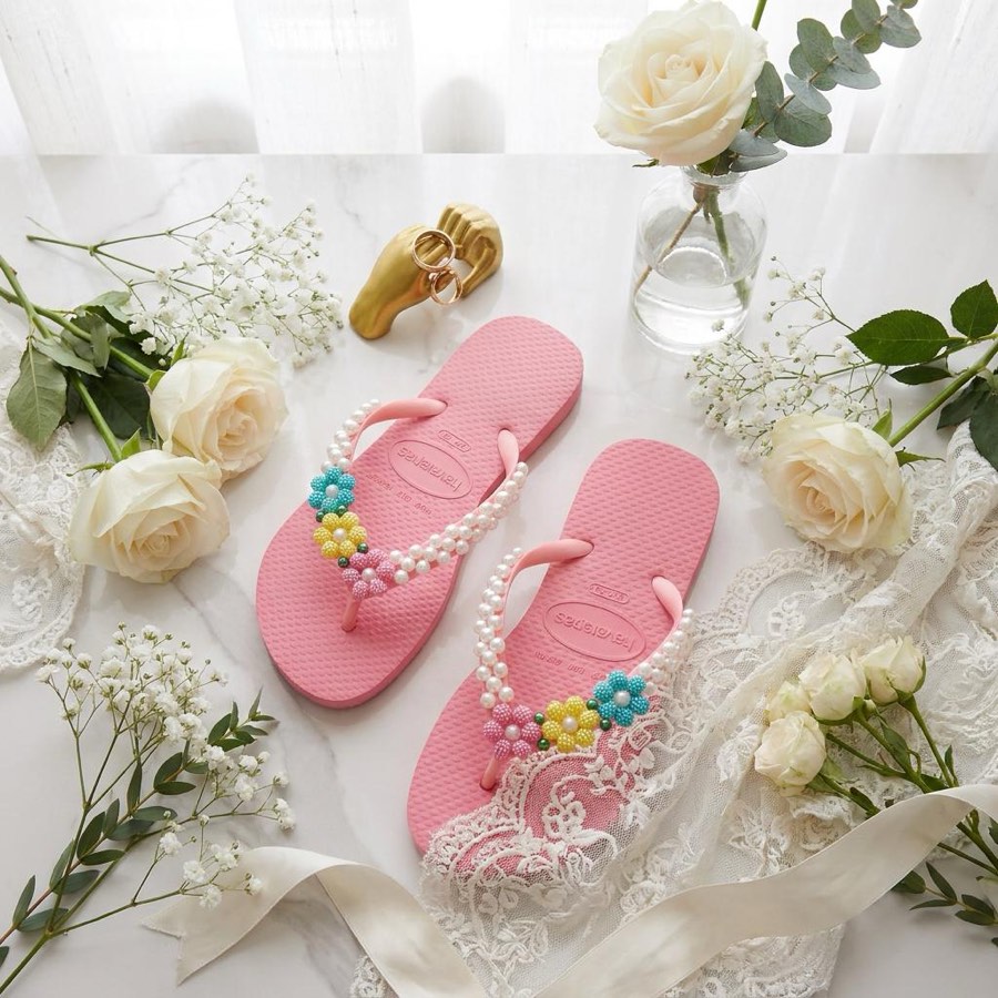 Chinelo Havaianas rosa com pérolas ao lado de caixas de presente